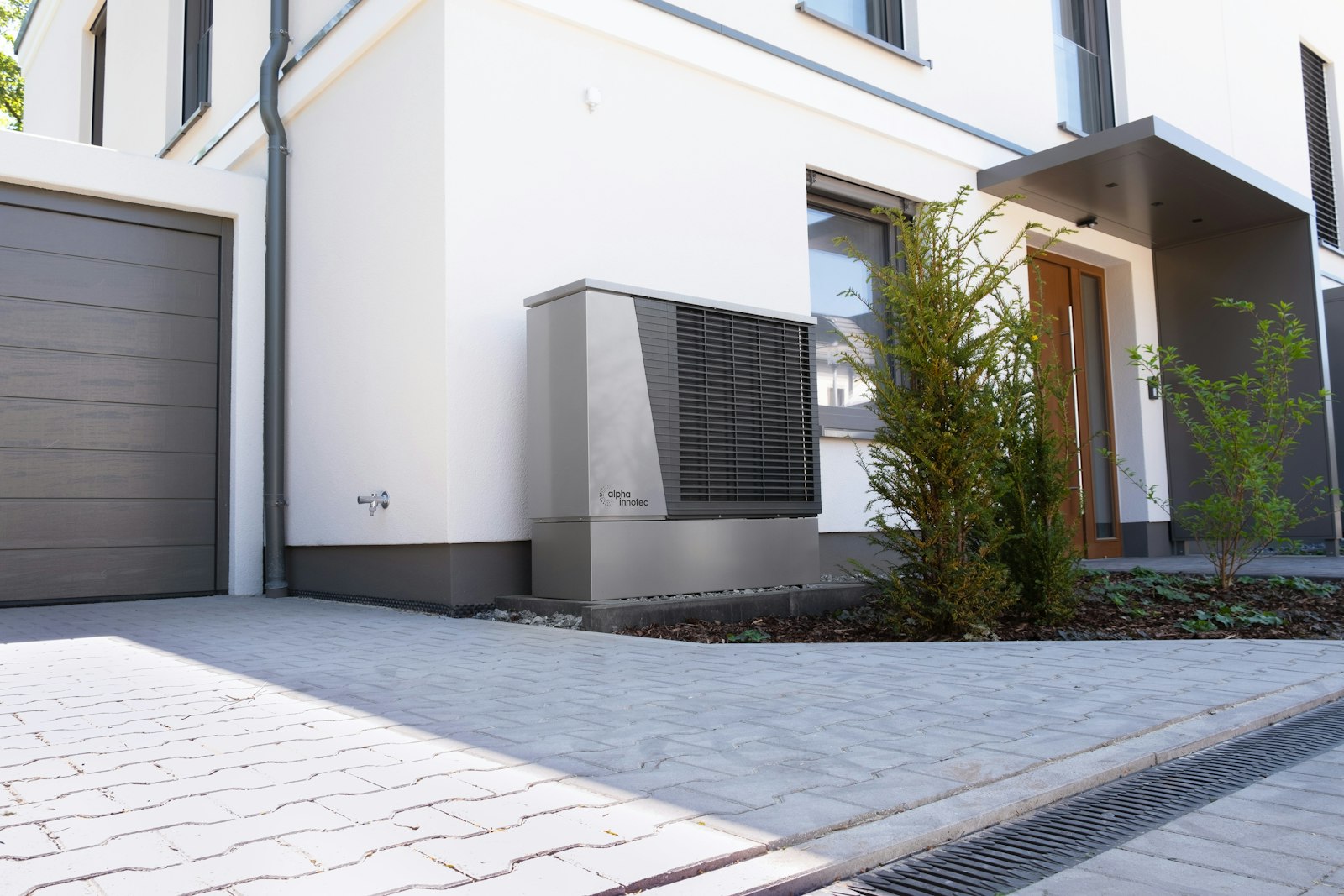 Moderne Luft-Wärmepumpe an der Außenwand eines Wohnhauses